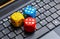 Three colorful wooden game dice showing six laying on a modern laptop keyboard. Lots of dice showing six, winning, lucky number