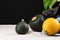 Three colorful zucchinis and basil on a black background. Organic vegetables for healthy salads on a white tablecloth.