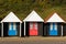 Three colourful beach huts with blue and red doors in a row