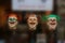 Three colourful fake laughing woman heads floating midair with different haircuts