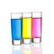 Three colourful shot drinks on a white background with reflections