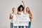 Three confident diverse women in white shirt and jeans looking cheerful while holding, standing with a banner in their