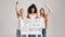 Three confident diverse women in white shirt and jeans looking serious while holding, standing with a banner in their