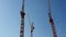 Three construction cranes that stand side by side against the blue cloudless sky. The view from the pleasure boat