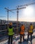 three construction workers are standing on top of a building looking at a construction site