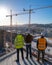 three construction workers are standing on top of a building looking at a construction site