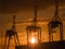 Three container cranes silhouetted against rising sun