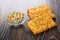 Three cookies with sunflower seeds and bowl with peeled seeds on dark wooden table