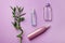 Three cosmetic botlles with bamboo branch on purple paper background