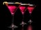 Three cosmopolitan drinks in line on black counter