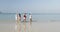 Three Couples Running On Beach To Water Holding Hands Happy Cheerful Men And Women Tourists On Vacation