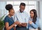 Three coworkers stand and discuss workplace issues with digital tablet, smiling