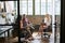 Three coworkers in a team meeting, seen through open door