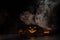 Three creepy Halloween grinning pumpkins glow in the dark among the fog. jack-o-lantern in a witch hat on a black