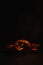 Three creepy halloween steaming pumpkins with a carved luminous smirk on a black background. A handmade jack-o-lantern