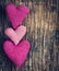 Three crochet pink hearts on wooden background