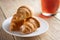 Three croissants on a white plate next to a Cup of tea