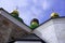 Three crosses on golden green domes against a blue sky white clouds.