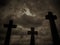 Three crucifix tombstones rising against a cloudy sky