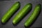 Three cucumbers on a dark stone background vegatarian health fruit vegetables dark stone background