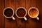 Three cups of espresso, freshly ground coffee and coffee beans on a wooden table