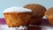 Three curd cakes sprinkled with chocolate and icing sugar on a pink plate, on a blue background close-up. Dessert, a small cupcake