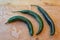 Three curved Chilaca peppers nesting on a weathered wood background, rustic food