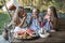 Three cute happy smiling girls, sisters, fiends, sitting at the table on vintage wooden bench and eating watermelon