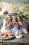 Three cute happy smiling girls, sisters, fiends, sitting at the table on vintage wooden bench and eating watermelon