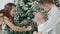 Three cute kids walking around christmas tree in living room.