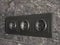 Three dark black rosettes in a dark marble wall