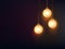 Three decorative light bulbs hanging against dark background