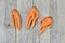 Three deformed carrots on a grey wooden rustic background. Concept ugly vegetables