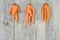 Three deformed carrots on a grey wooden rustic background. Concept ugly vegetables