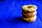 Three delicious donuts folded in a pyramid on a table of painted blue boards.