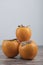 Three delicious fuyu persimmons placed on wooden table