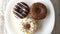 Three delicious sweet donuts rotating on a plate. Rustic wooden table. Looped.