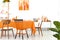 Three different chairs placed by the long dining table with orange