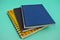 Three different colored paper diaries isolated on a light blue paper background