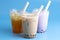 Three Different Types of Boba Tea on a Bright Blue Background