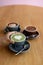 Three different types of coffee on a wooden board which are matcha, chcoolate and mocha lattes