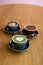 Three different types of coffee on a wooden board which are matcha, chcoolate and mocha lattes