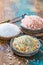 Three different types of natural salt in stone bowls on wooden s