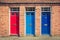 Three differently coloured front doors at the entrance of old En