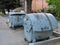 Three dirty trash containers near the sidewalk. Stock photo