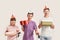 Three disabled children wearing birthday caps smiling at camera and holding presents while celebrating birthday together