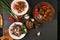 Three dishes stand on dark stone background.