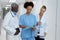 Three diverse male and female doctors standing in hospital corridor looking at medical documentation