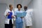 Three diverse male and female doctors standing in hospital corridor looking at medical documentation