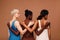 Three diverse women standing against brown background